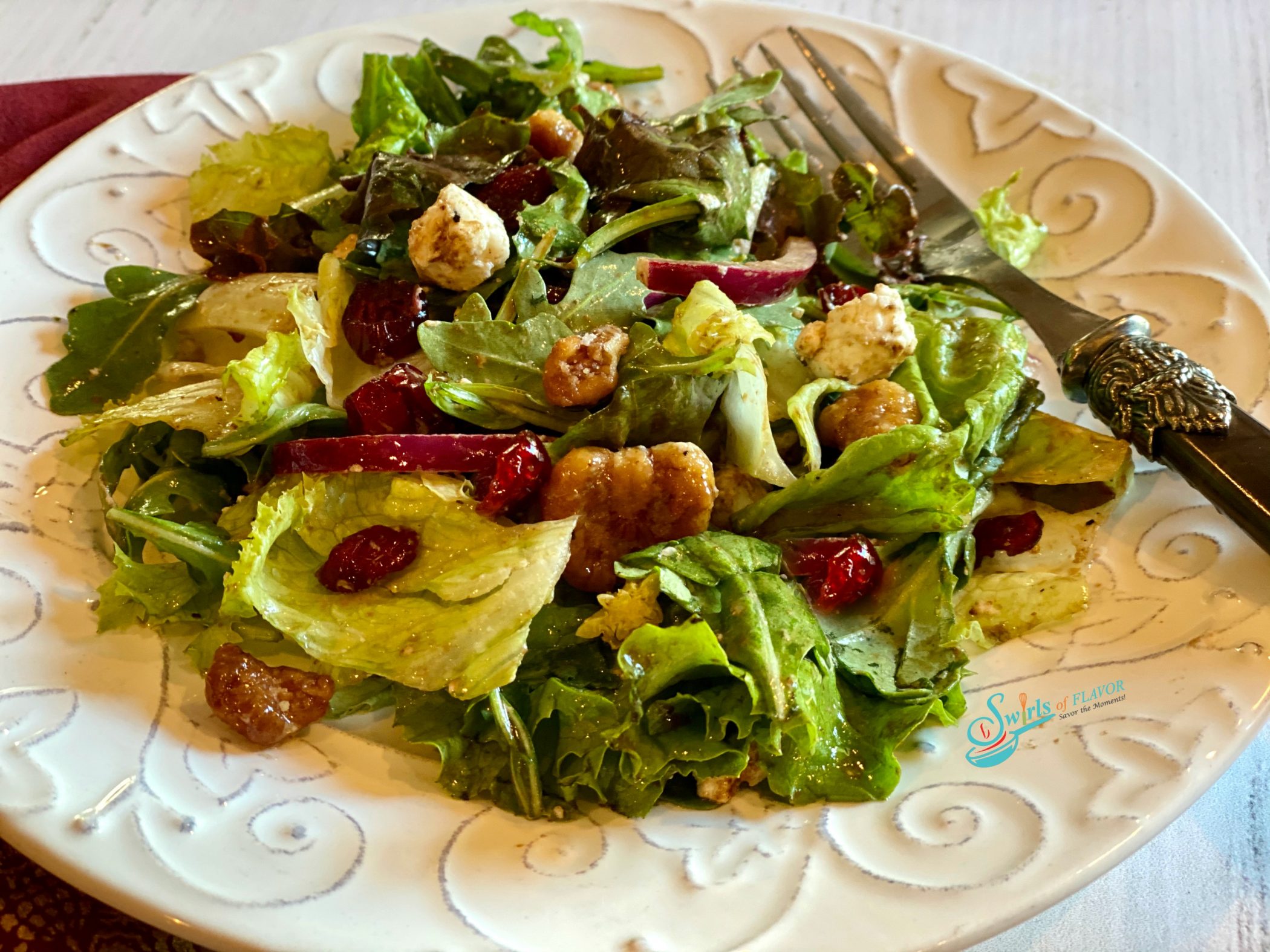 single serving of tossed cranberry salad with walnuts on white dish with fork