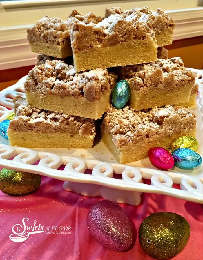 crumb cake pieces stacked on white platter with chocolate Easter egg candy
