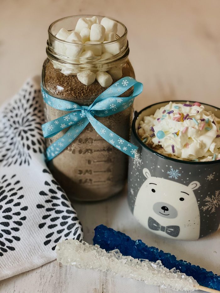 hot chocolate mix in jar with mug of hot chocolate and whipped cream