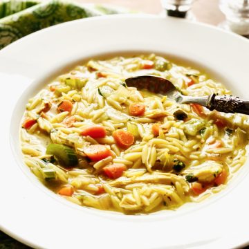 chicken orzo soup in white soup bowl with spoon