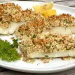 baked cod on platter with parsle and lemon wedges