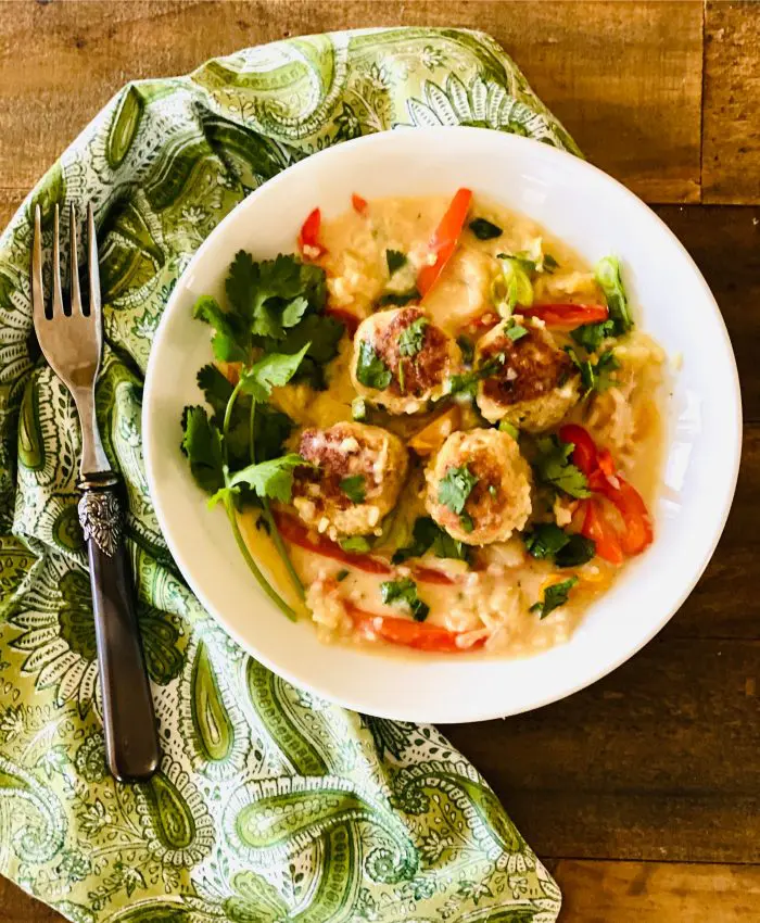 chicken meatballs recipe in white bowl with rice, bell peppers and cilantro