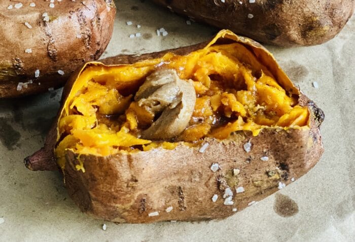 one baked sweet potato cut open with brown sugar butter