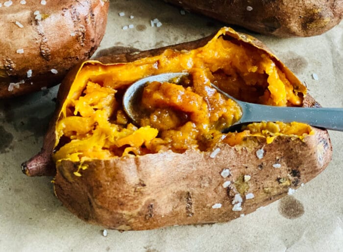 scooping a baked sweet potato with a spoon