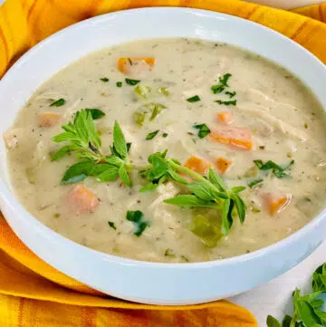 creamy chicken soup in a white bowl with fresh herb garnish