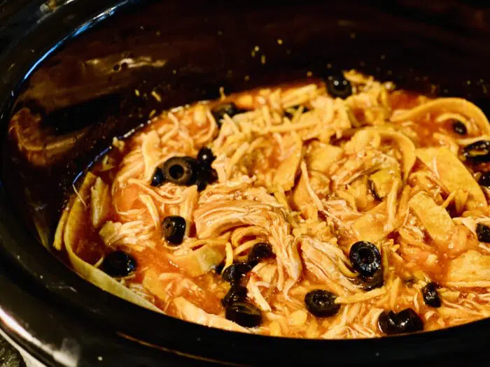 shredded chicken in enchilada sauce with cheese and olives