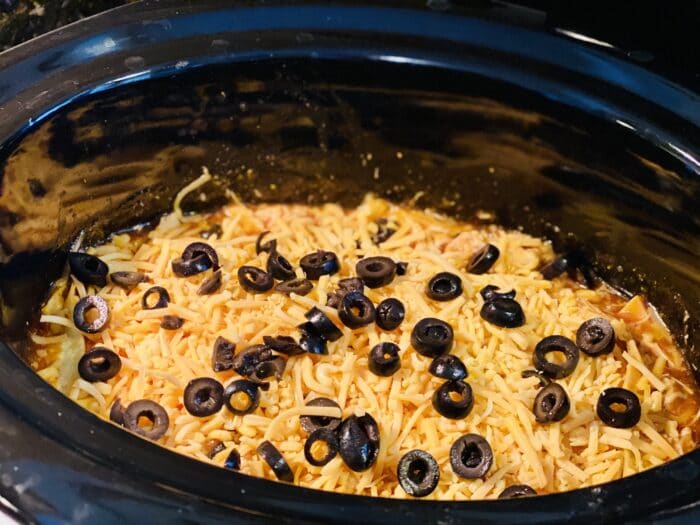 cheese and olives stirred into chicken enchilada mixture