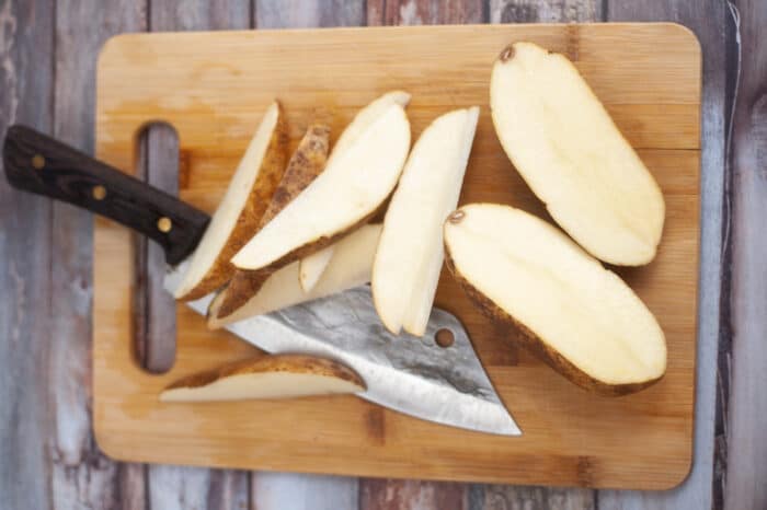 potato slices with knife on cutting board