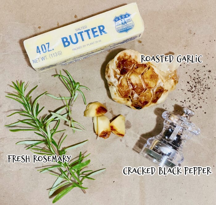 butter, fresh rosemary, roasted garlic and cracked black pepper on parchment paper