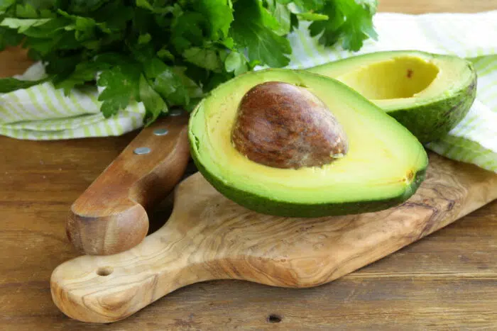 avocado cut in half on wooden board