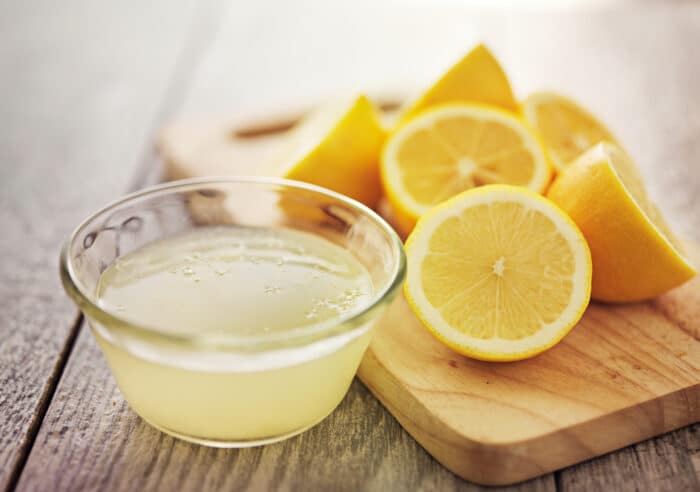 lemon juice in a glass bowl with cut lemons