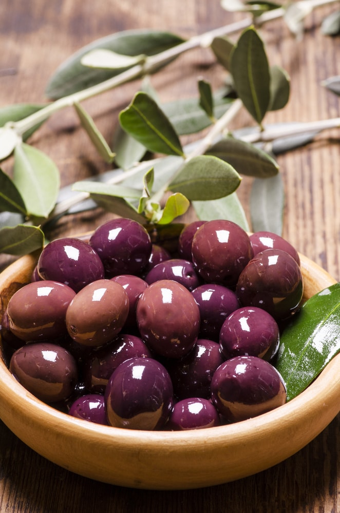 olives in a wooden bowl with branches