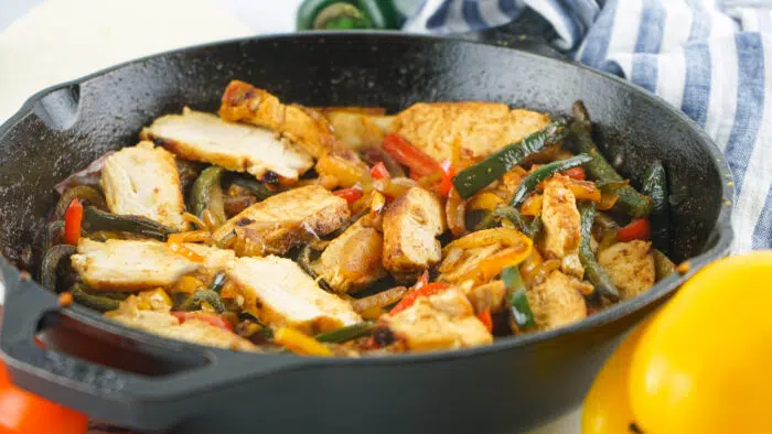 sliced chicken and vegetables in cast iron skillet