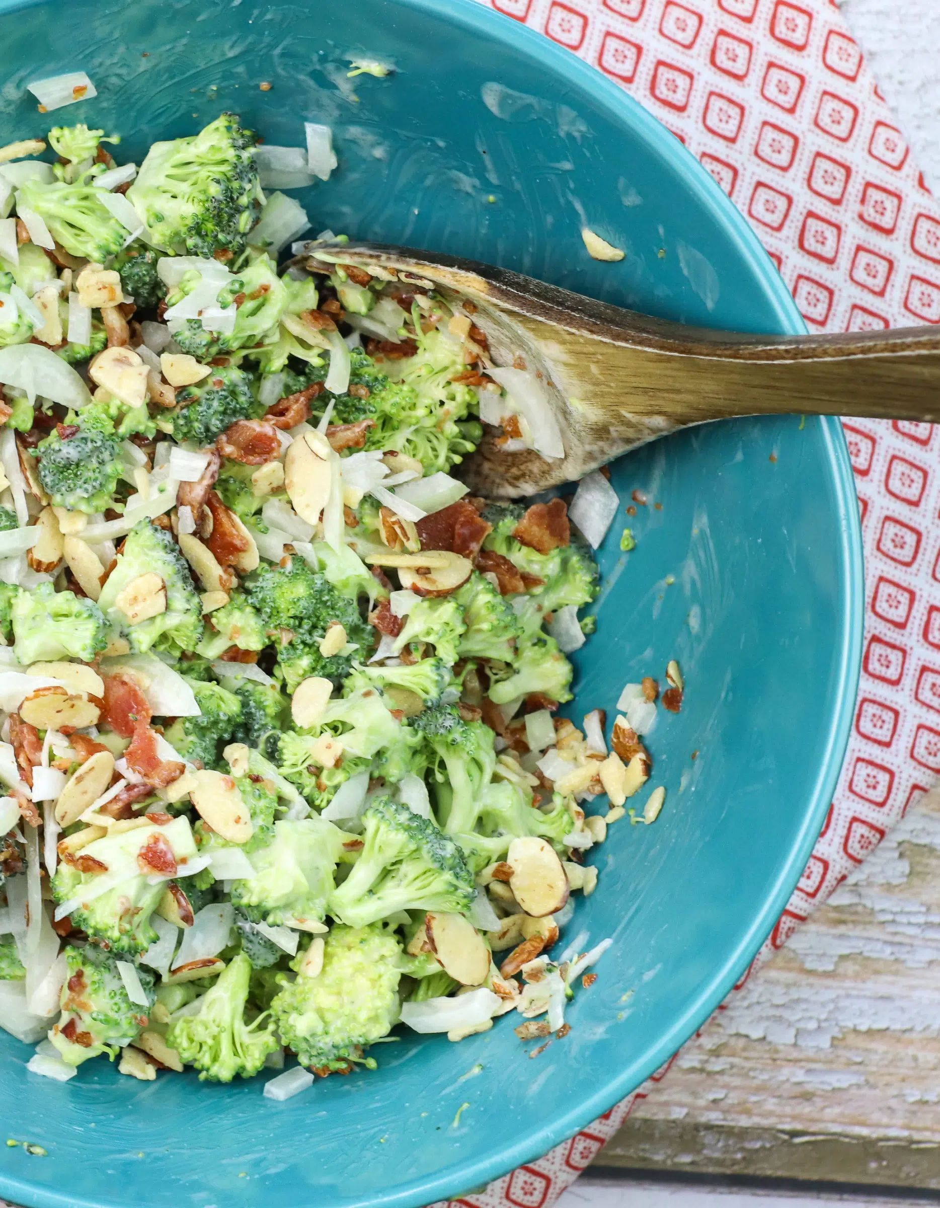 bowl of broccoli salad with wooden spoon