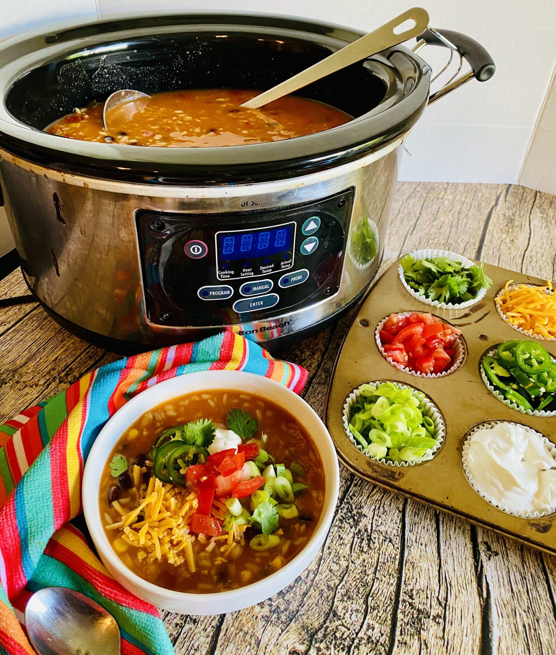 slow cooker with bowl of soup and taco toppings