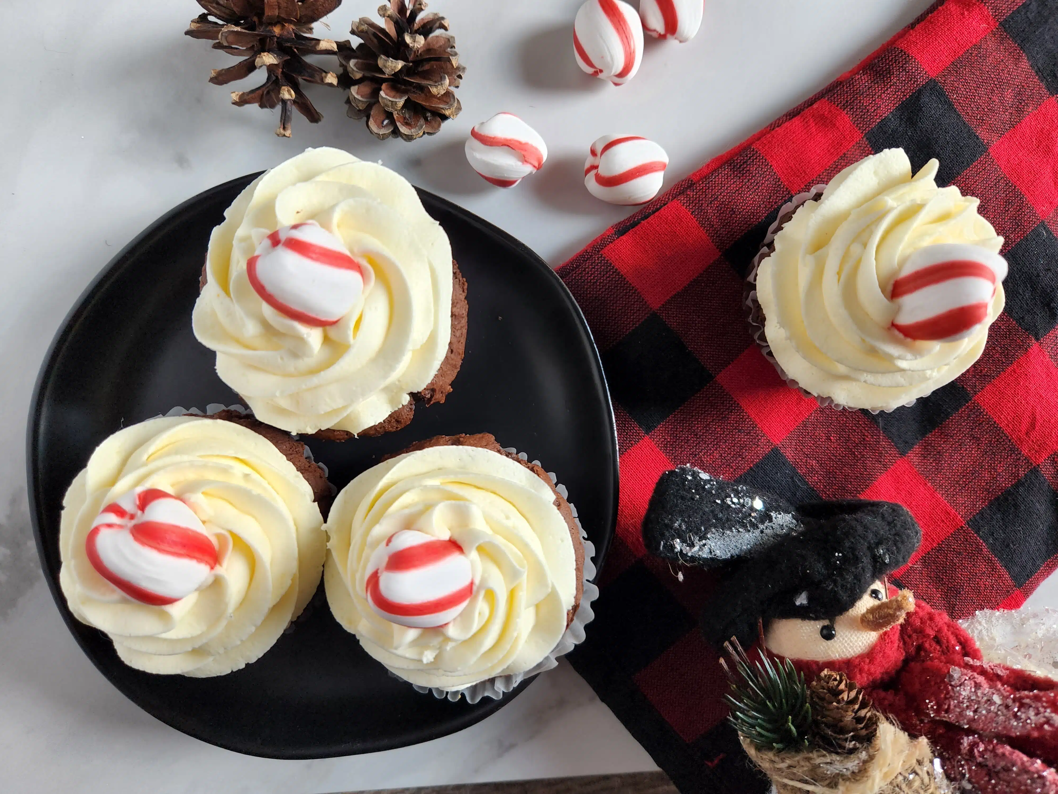 four chocolate cupcakes with peppermint frosting on a black plate