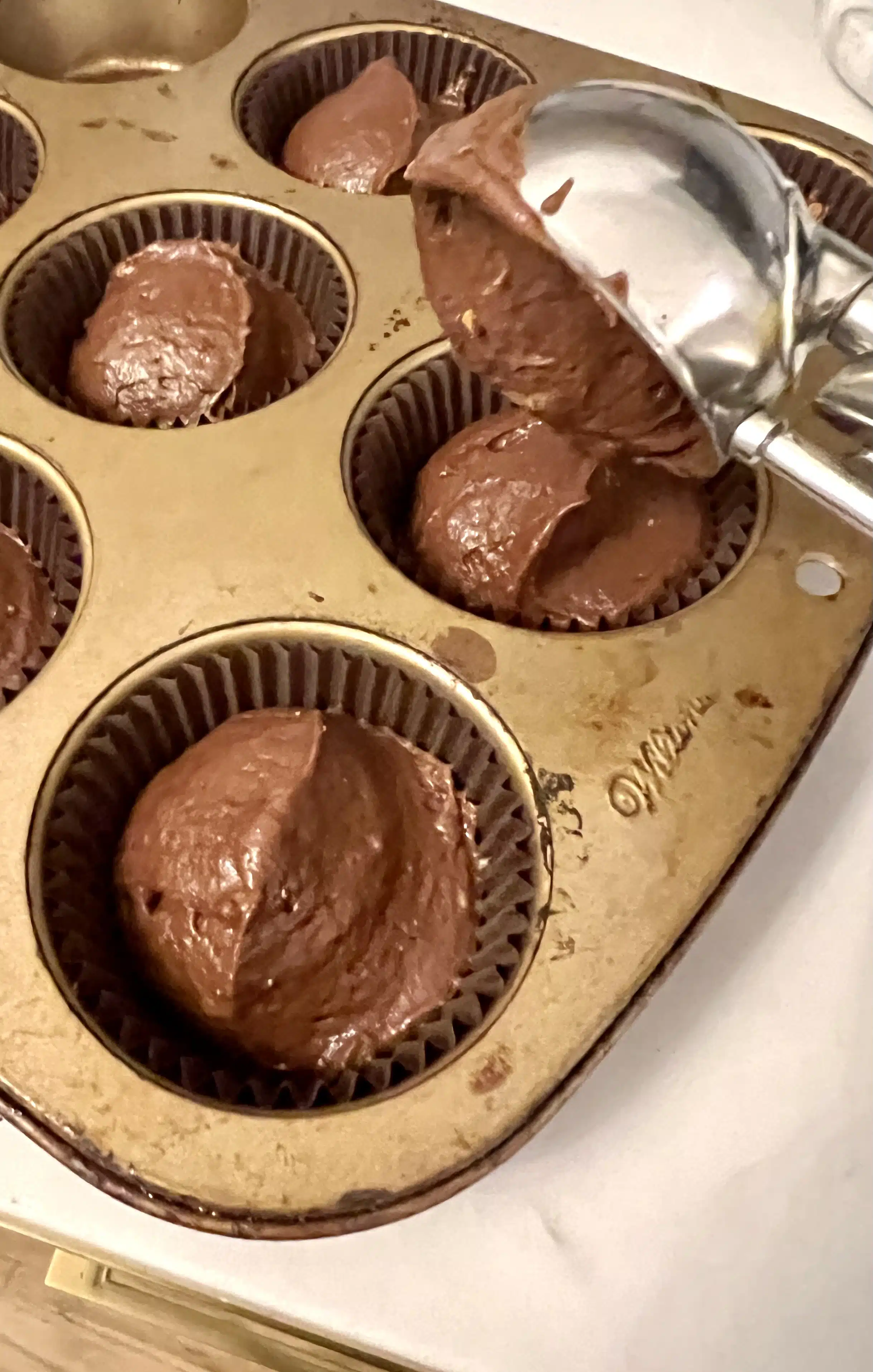 cupcake batter in pan with scooper
