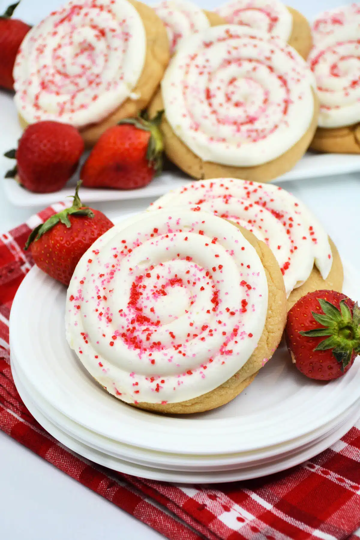 frosted strawberry cookies on a stack of plates