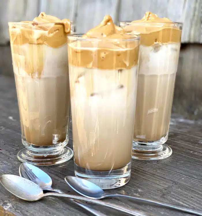 three glasses of iced dalgona coffee with spoons