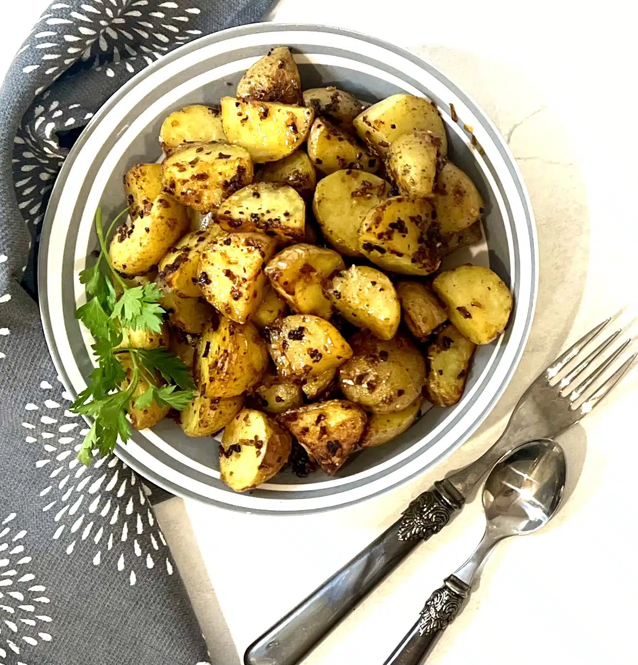 overhead photo of roasted potatoes in a bowl with utensils