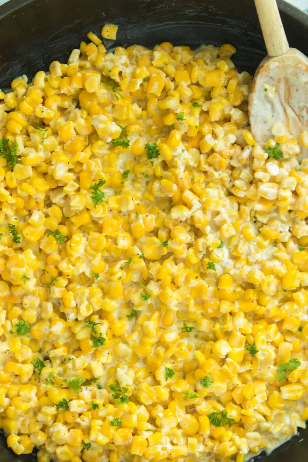 creamy corn with parsley with wooden spoon