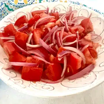 tomato and onion salad in a white bowl