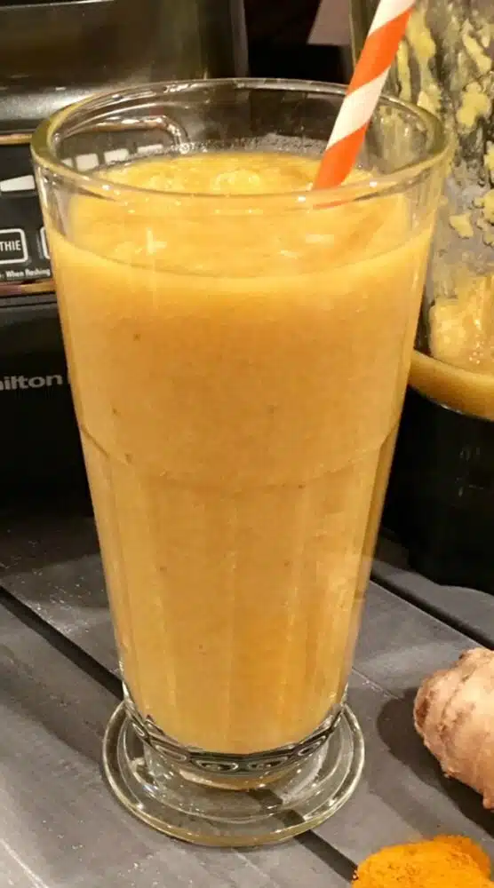 banana mngo smoothie in glass with a straw