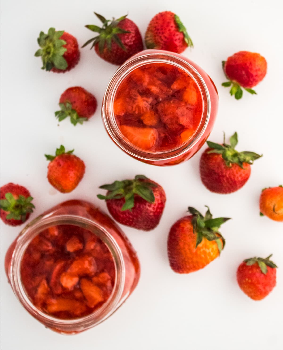 overhead picture of jam in jars with fresh strawberries