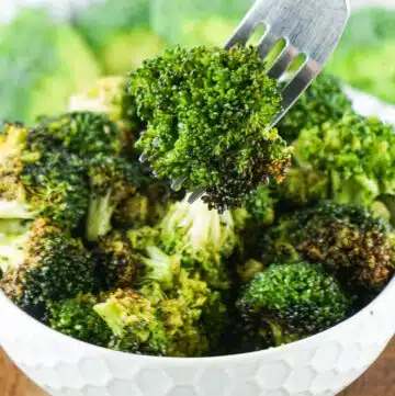 air fryer broccoli in white bowl with broccoli on a fork