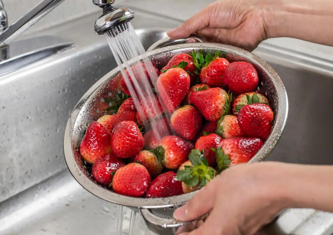 washing strawberries in a colander