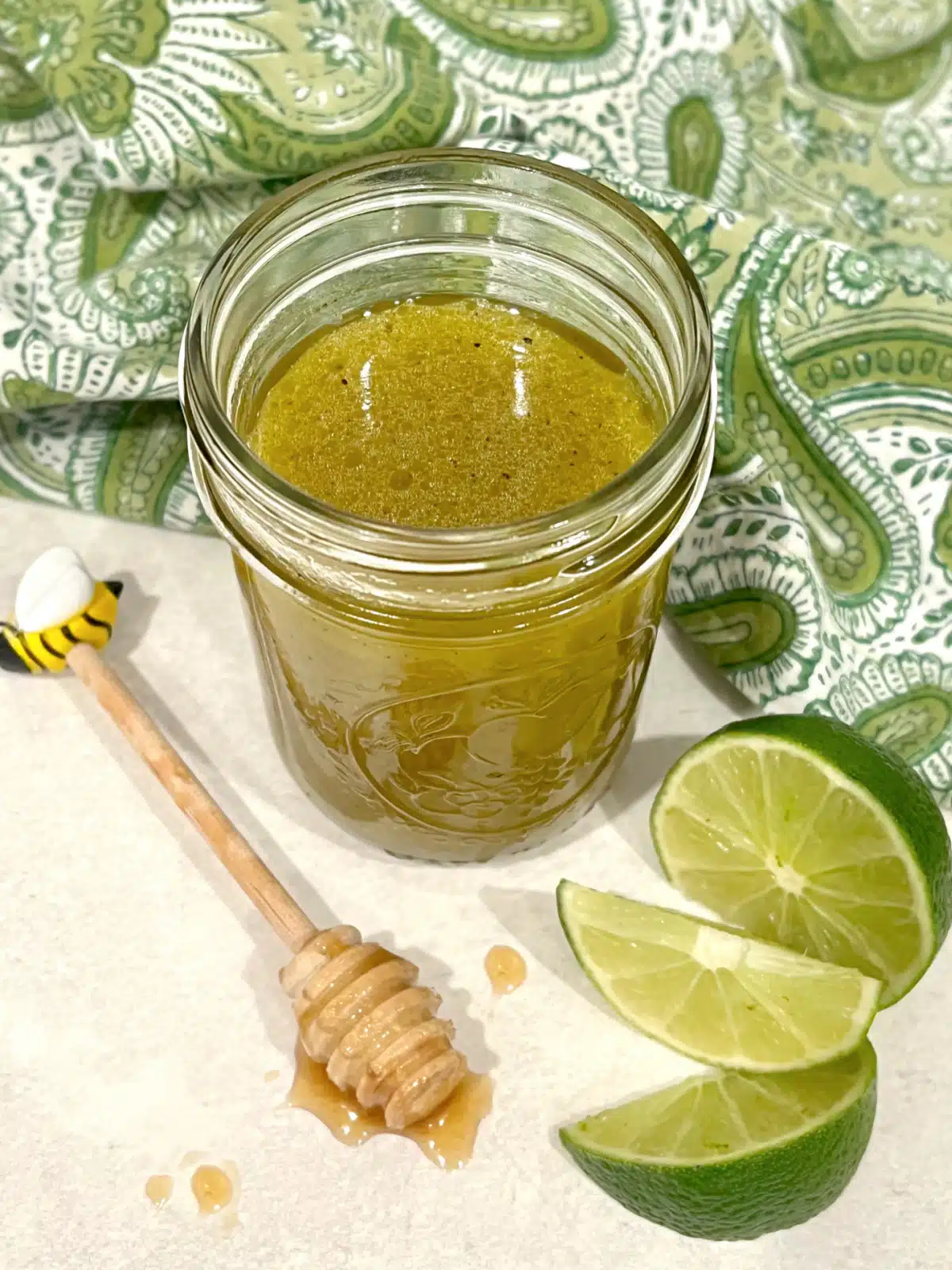 lime honey salad dressing in a mason jar with lime wedges