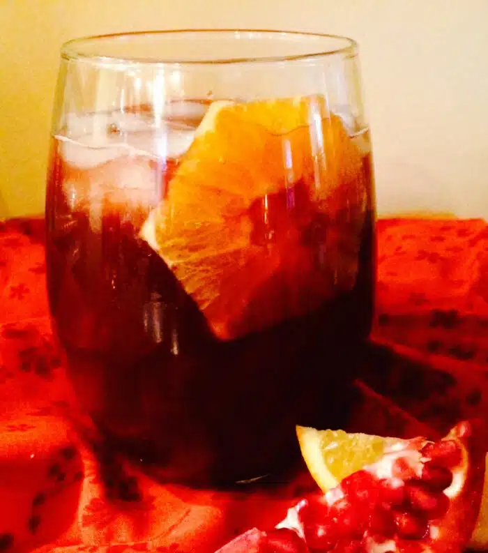 glass of bourbon punch with slice of orange