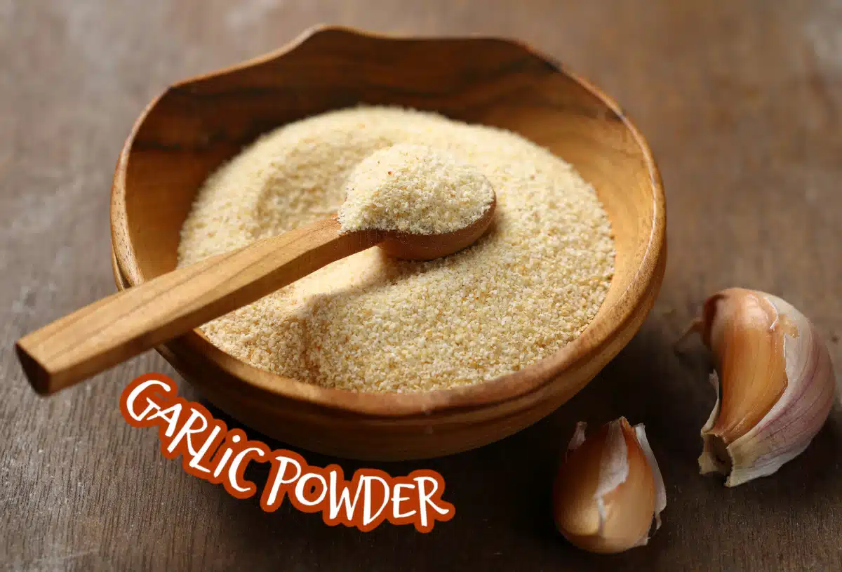 garlic powder in a wooden bowl with garlic cloves