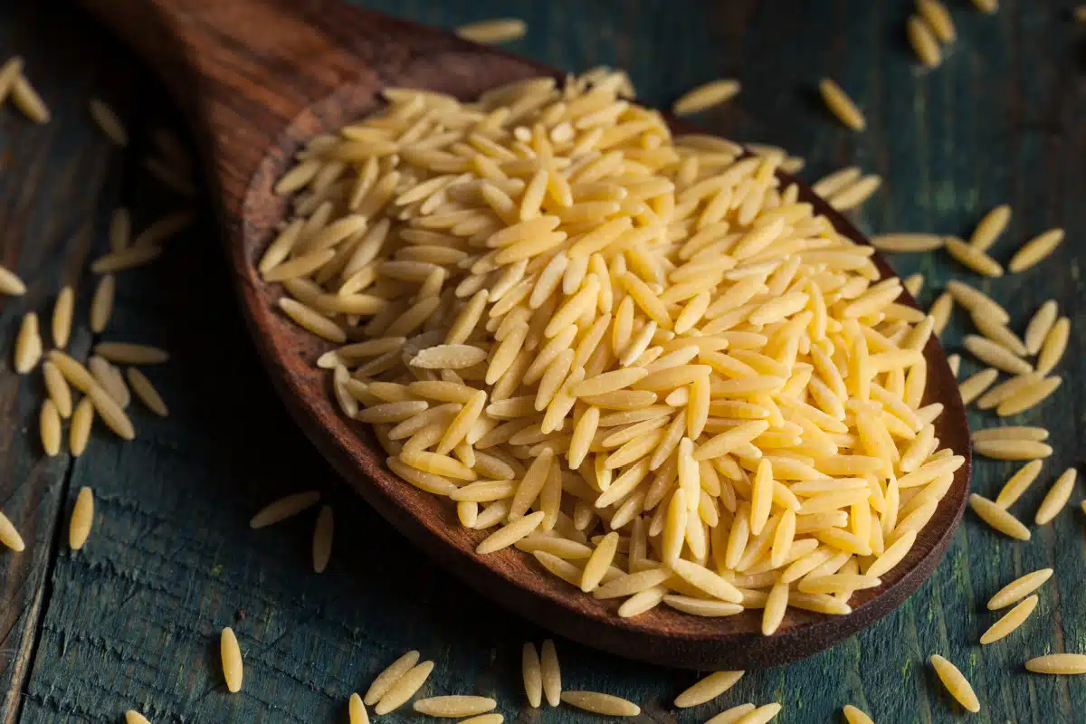 uncooked orzo on a wooden spoon