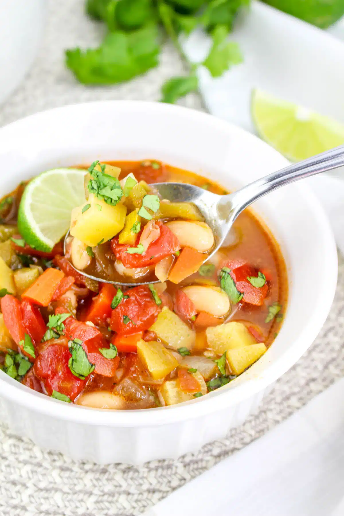 spoonful of bean chili with a lime wedge garnish and in a white bowl