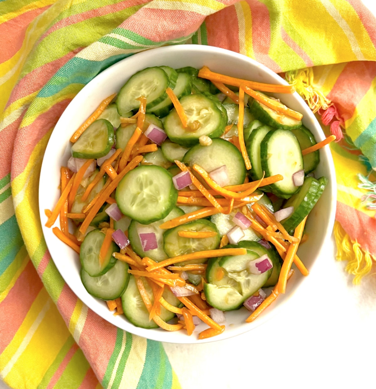 overhead photo of carrot and cucumber salad with a colorful napkin