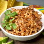shredded chicken taco meat in a bowl with fresh cilantro sprigs