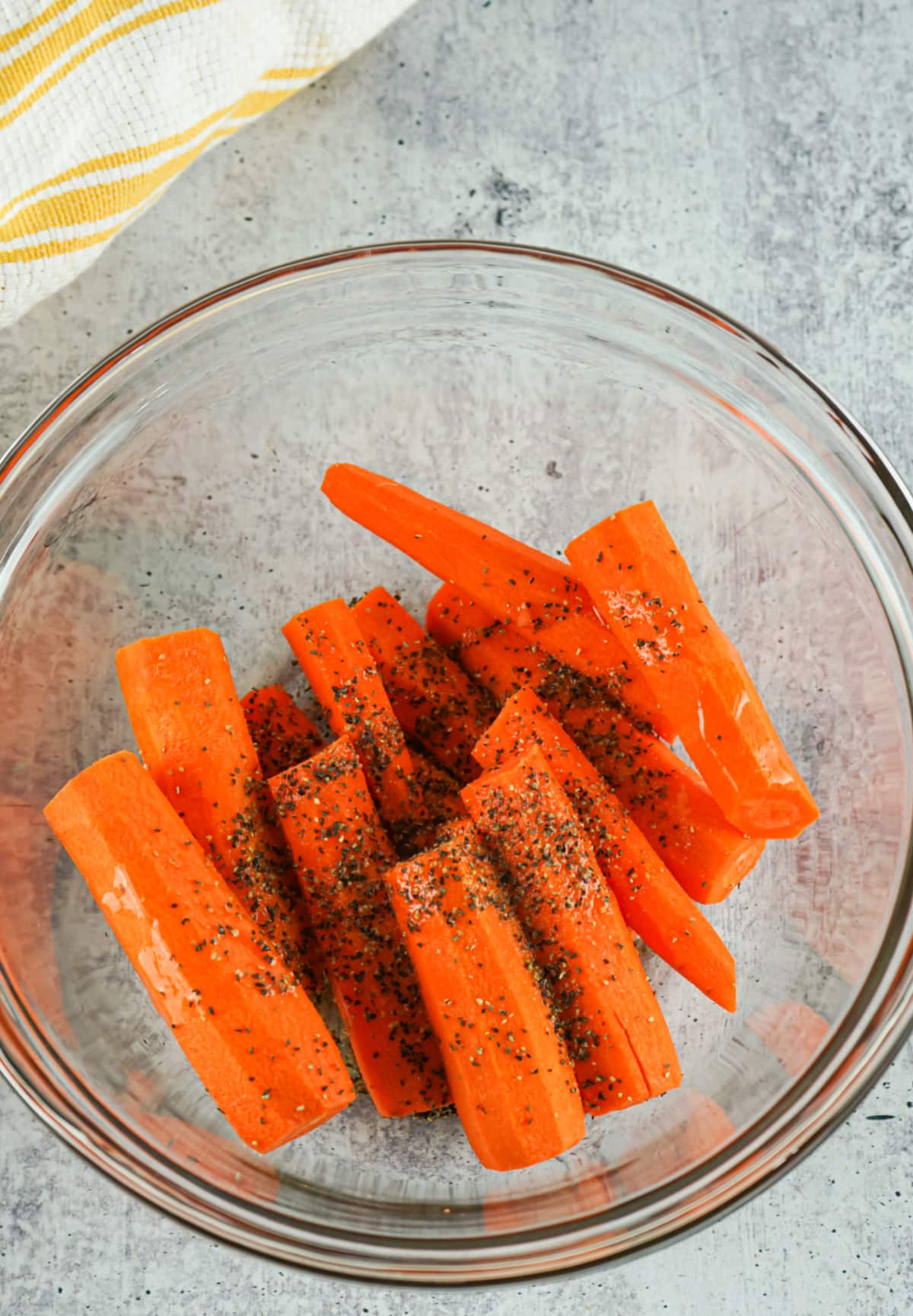 tossing carrots and seasonings in a mixing bowl