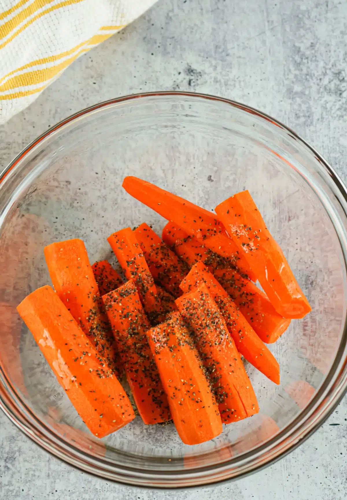 tossing carrots and seasonings in a mixing bowl