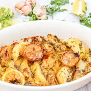 Greek lemon potatoes in a white casserole baking dish