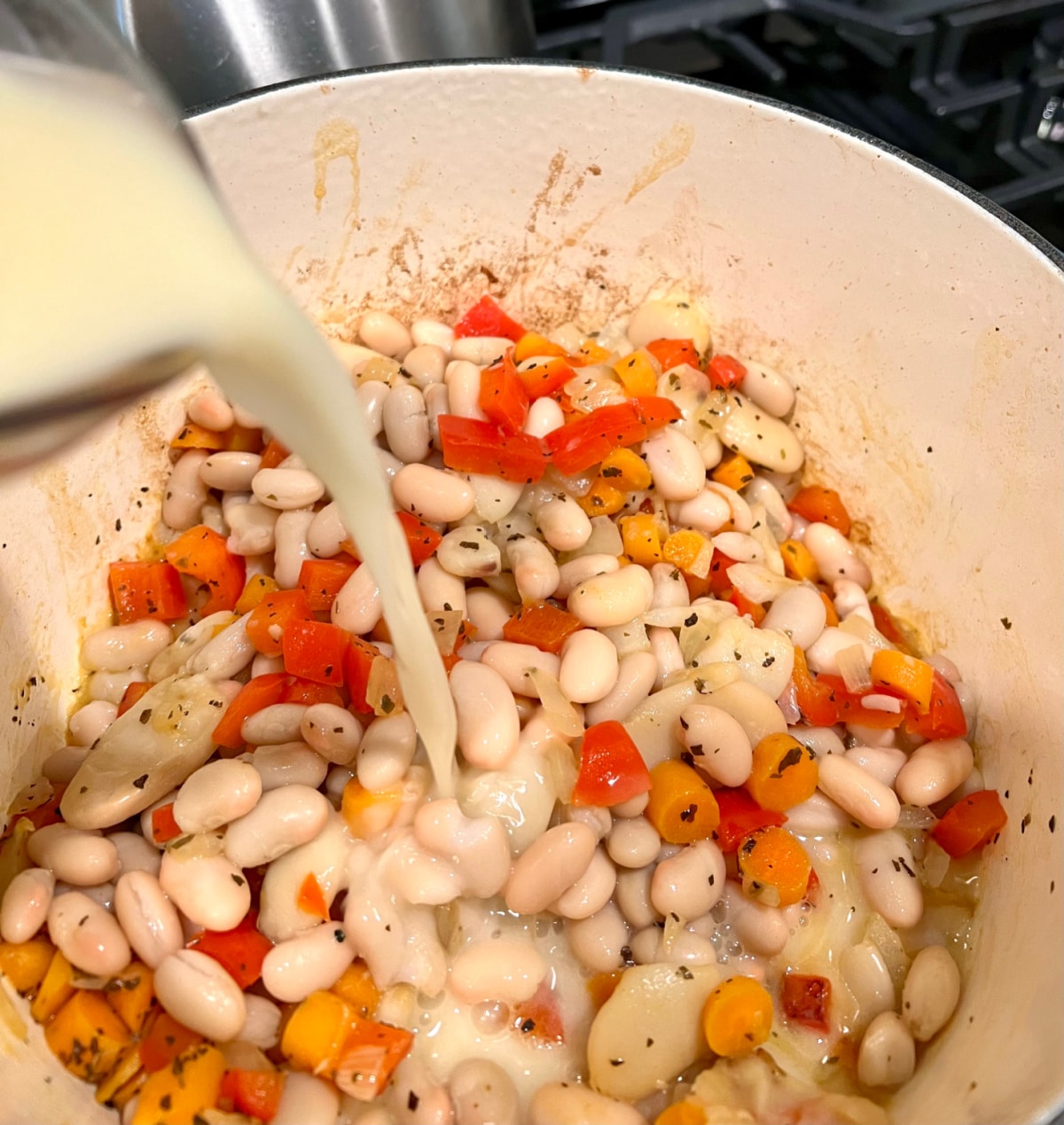 pouring broth mixture into ban and vegetables in a pot