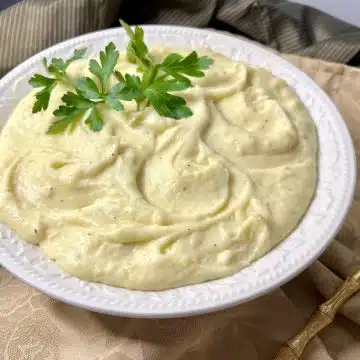 Boursin whipped potatoes in a bowl with fresh parsley sprig