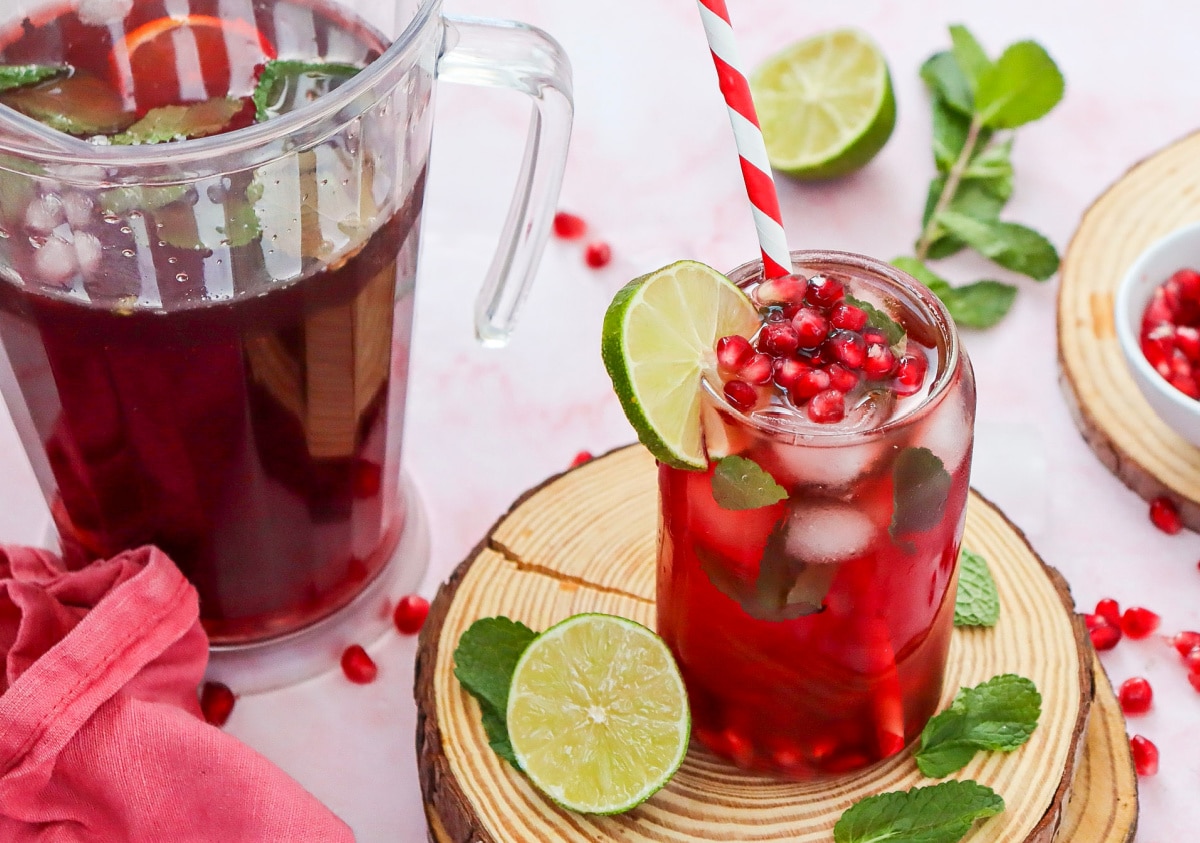 pomegranate mocktail in a glass with a pitcher