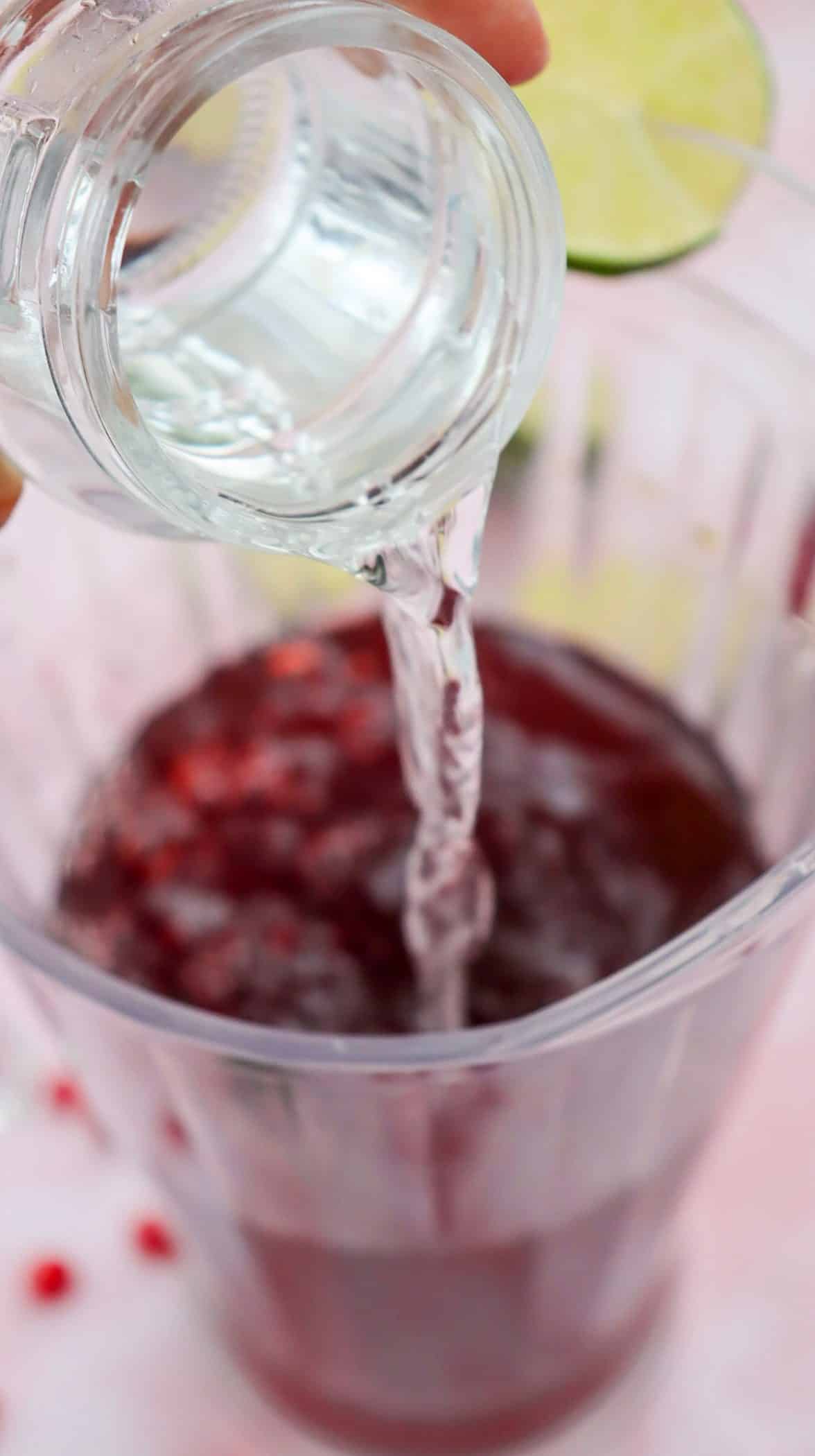 adding club soda to a pomegranate mocktail