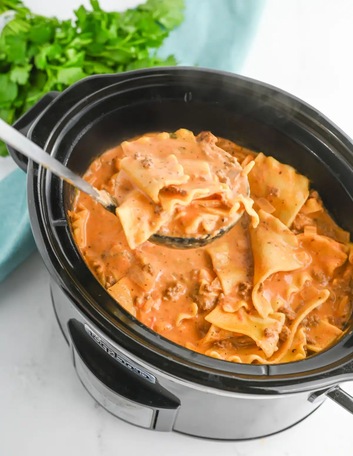 slow cooker lasagna soup in the crock pot with a spoon