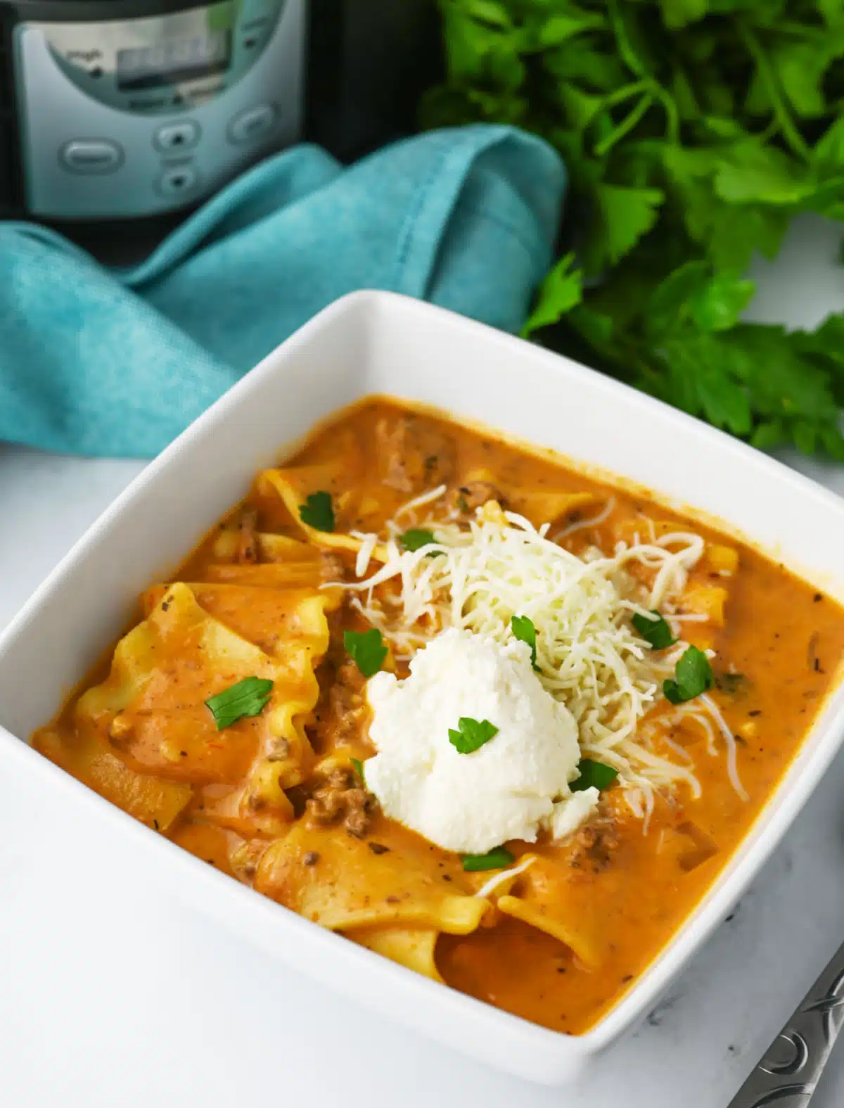 crock pot lasagna soup in a square white bowl with a blue napkin