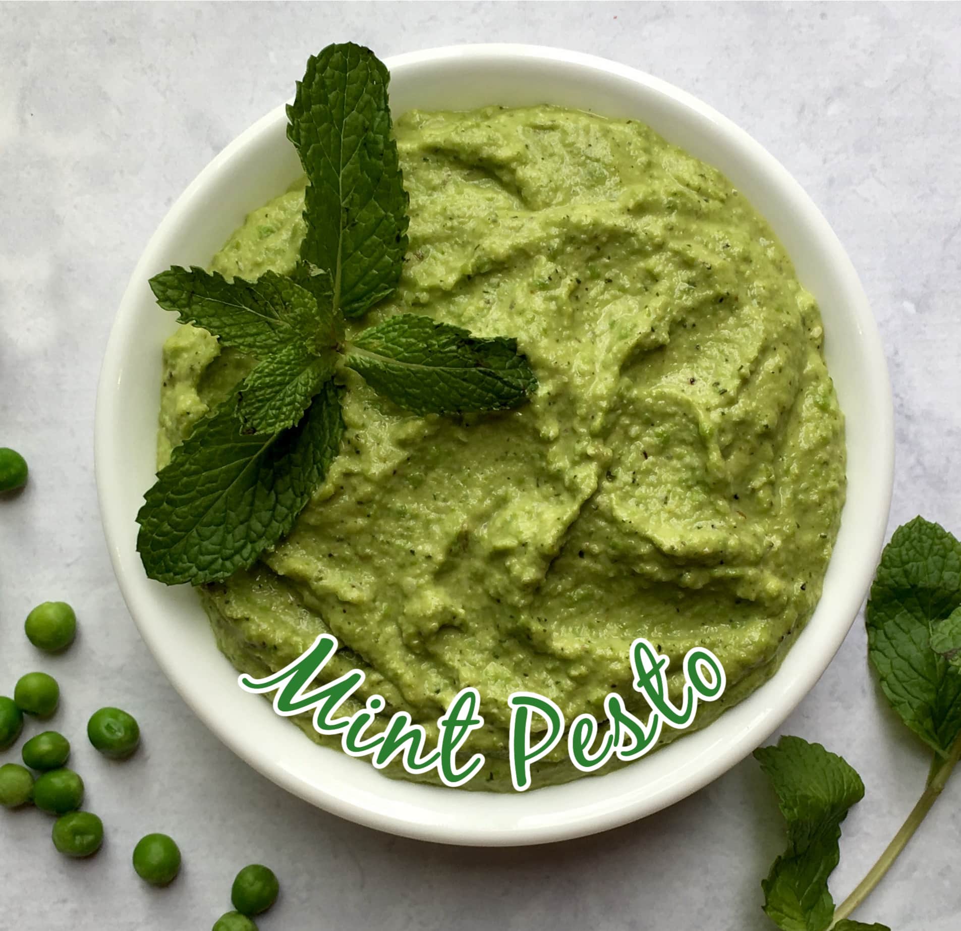 mint pesto in a bowl with a sprig of fresh mint