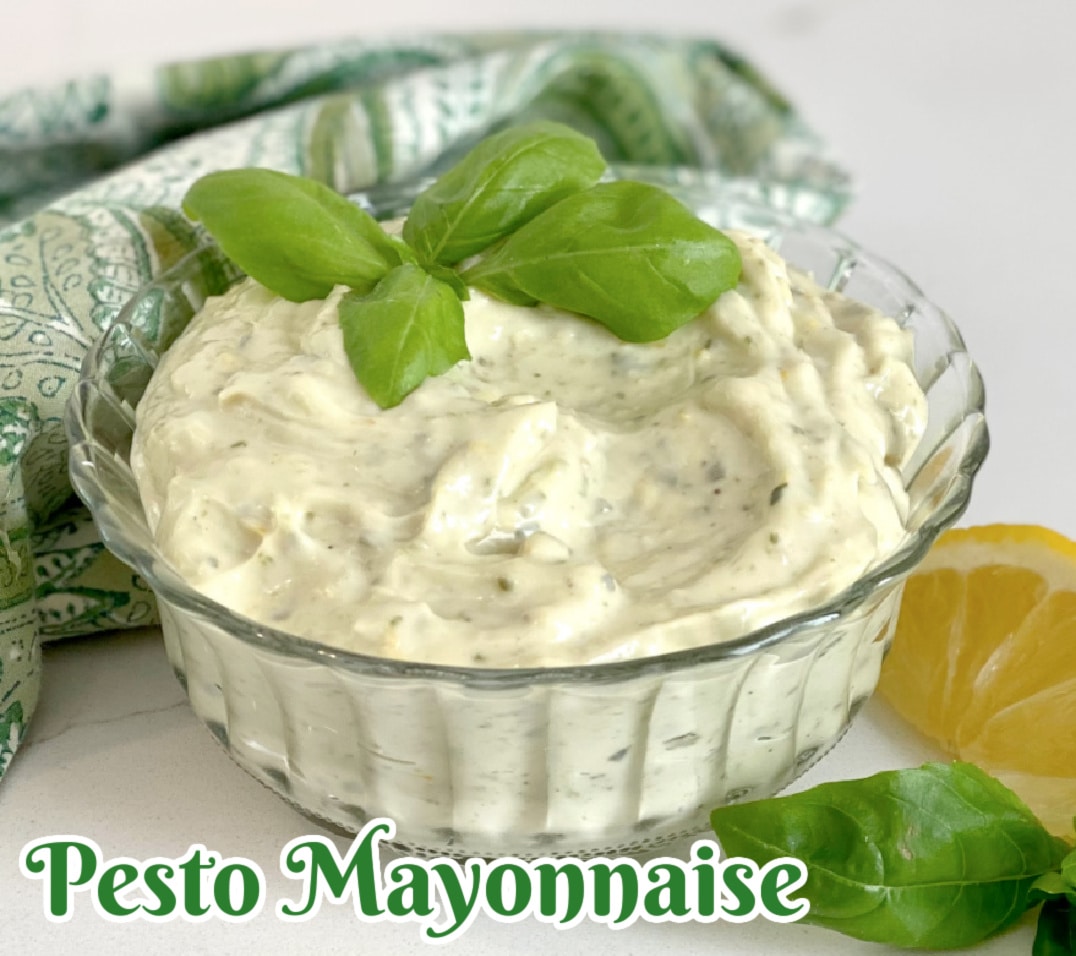 pesto mayonnaise in a glass bowl with sprig of fresh basil