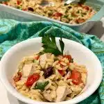 Baked chicken and orzo in a serving bowl with baking dish