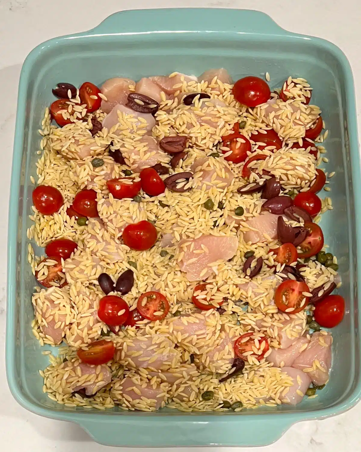 combining chicken, orzo and other ingredients in the baking dish